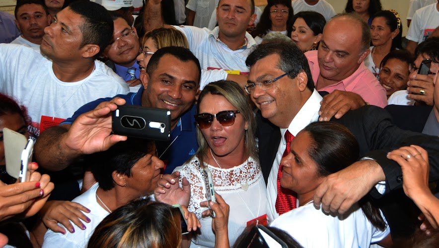 (O governador Flávio Dino, de gravata vermelha, tirando selfie com eleitores. Foto: Karlos Geromy/Ascom)